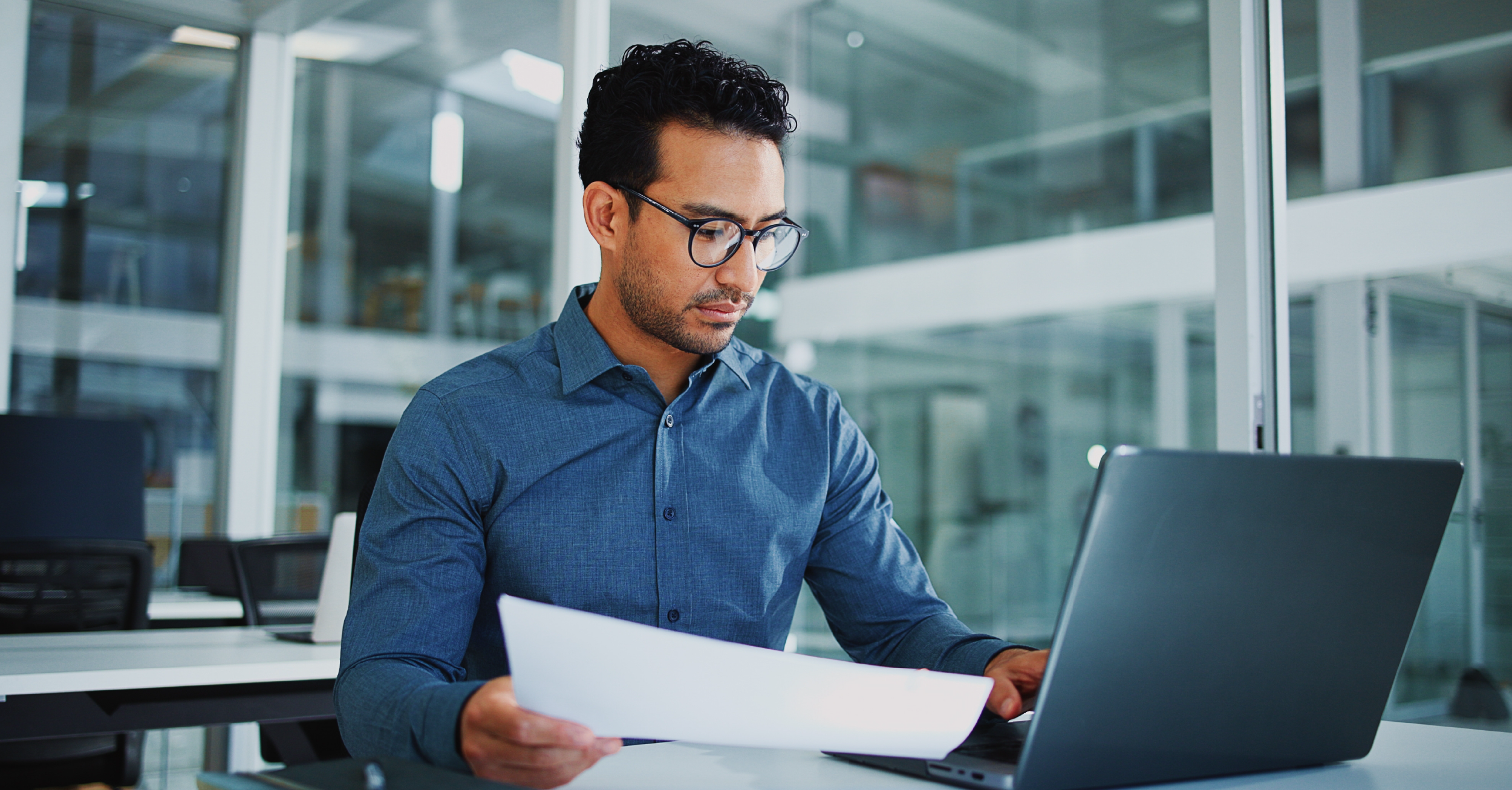 A man compares a sheet of paper to a laptop screen