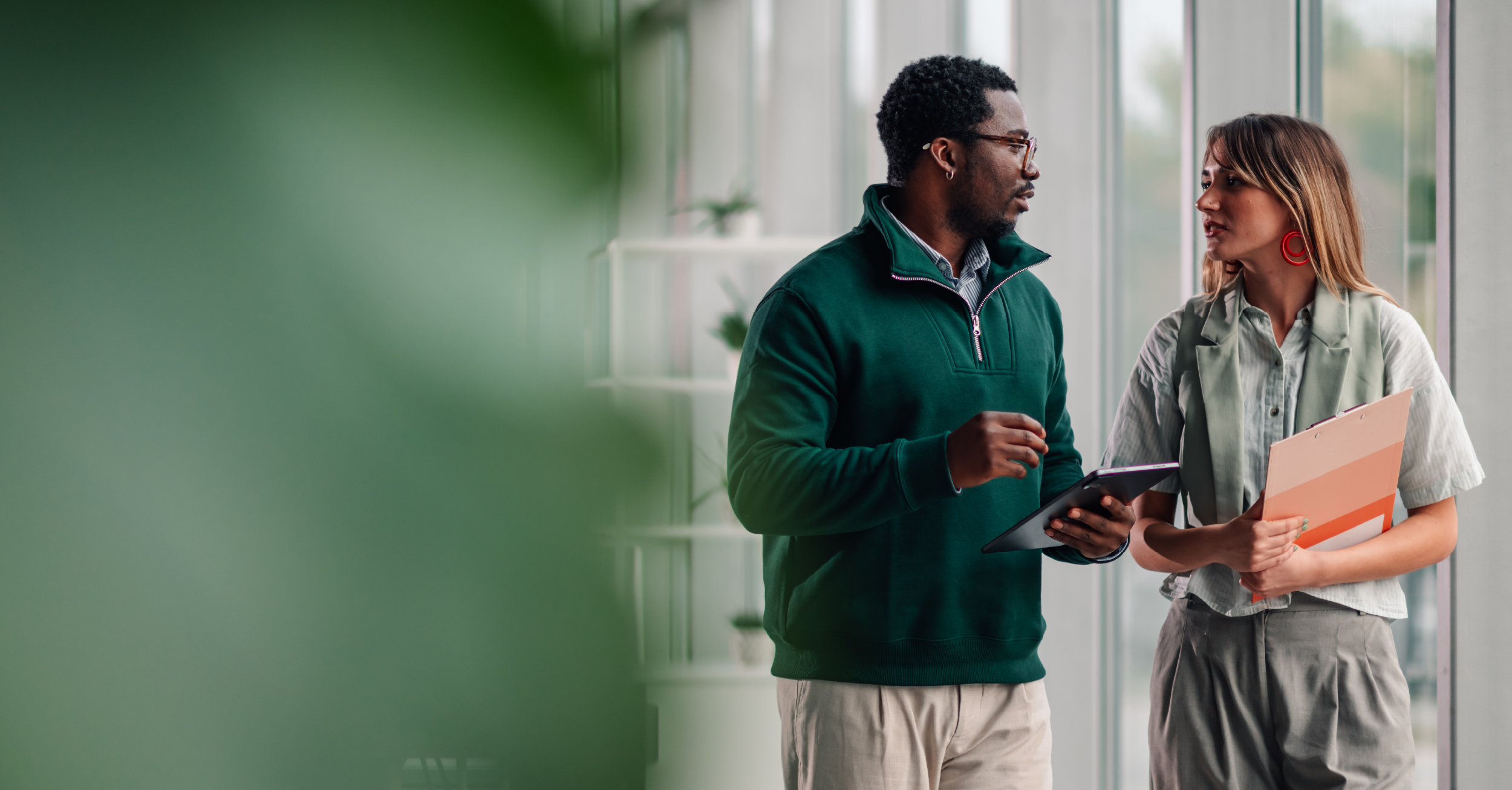 Two professionals talking in a modern office hallway